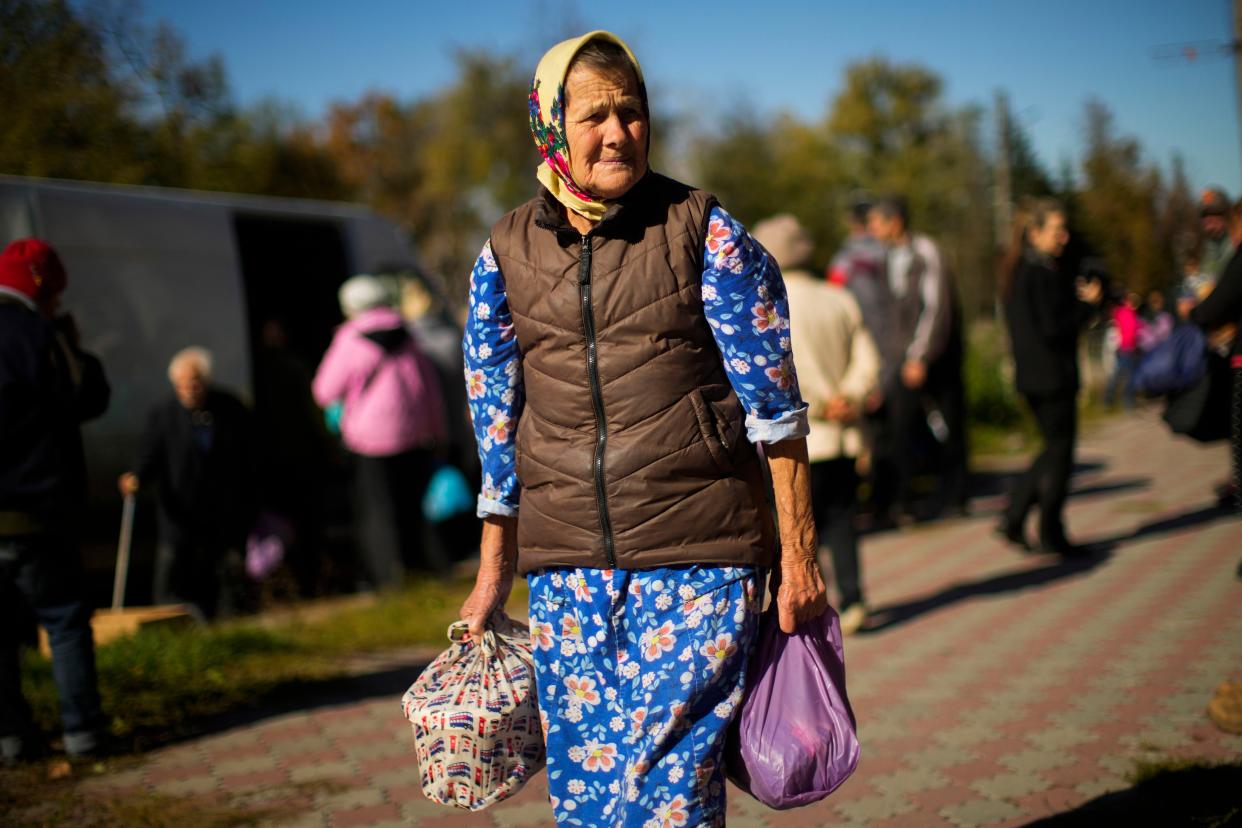 A woman carries bags with food given by Ukrainian volunteers in Izium, Ukraine, Wednesday, Oct. 12, 2022. Residents in Izium have been living with no gas, electricity or running water supply since beginning of September.