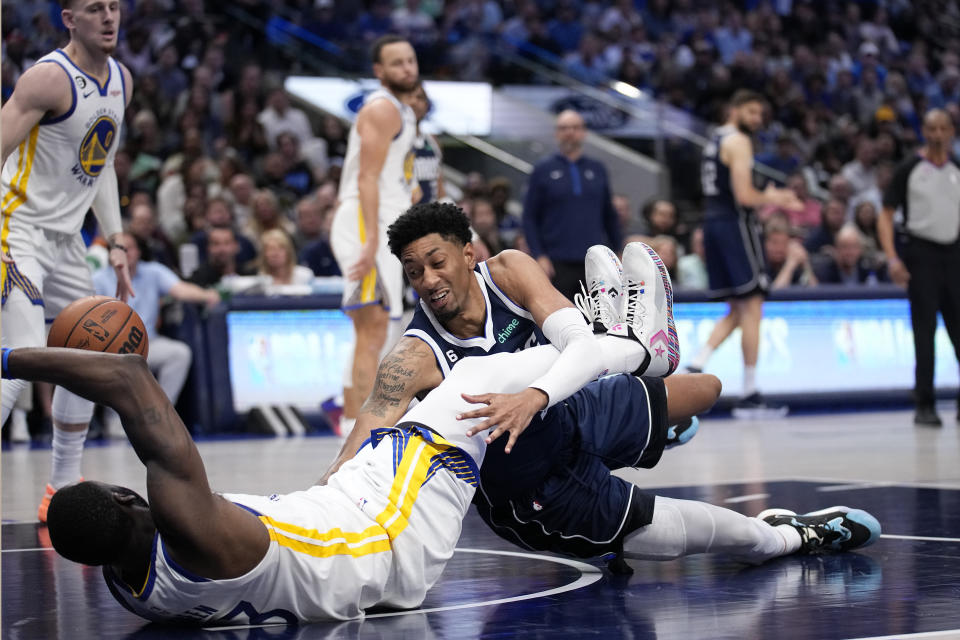 Golden State Warriors forward Draymond Green, bottom left, and Dallas Mavericks forward Christian Wood, bottom right, fall to the floor after colliding on a shot attempt by Wood in the seconc half of an NBA basketball game, Wednesday, March 22, 2023, in Dallas. (AP Photo/Tony Gutierrez)