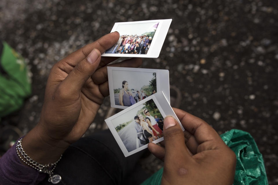 In this Nov. 3, 2018 photo, a member of a group of about 50 LGBTQ migrants traveling with the caravan hoping to reach the U.S. border, looks at polaroids taken by a colleague who is documenting their journey, on the road to Sayula, Mexico. The LGBTQ migrants traveling together, most of them in their 20s but some as young as 17 or as old as 60, say they banded together for safety in numbers, a sort of caravan within the caravan. (AP Photo/Rodrigo Abd)