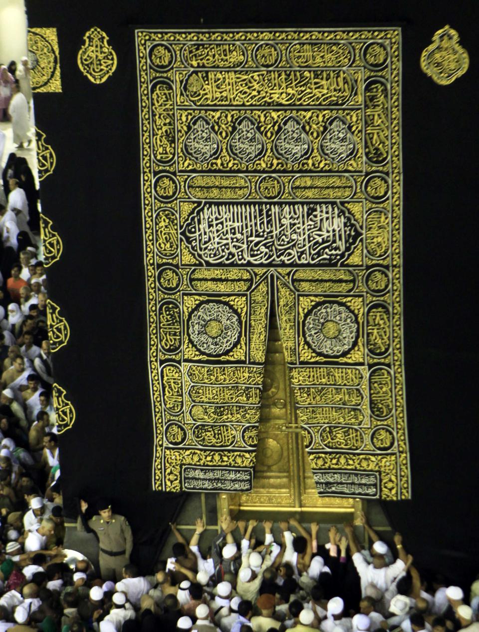 Muslims touch and pray at the door of the Kaaba at the Grand Mosque in the holy city of Mecca