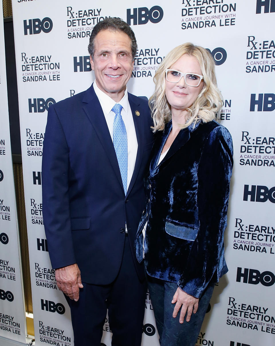 Two people posing together at an event with a branded backdrop