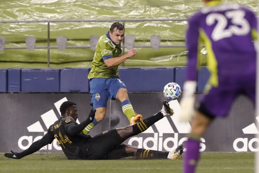 Los Angeles FC defender Jesus David Murillo, left, slides across on a tackle attempt on Seattle Sounders.