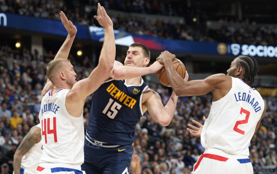 Denver Nuggets center Nikola Jokic drives to the basket between Clippers center Mason Plumlee and forward Kawhi Leonard.
