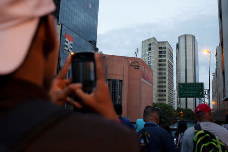 People look at the damage on the top five floors of an abandoned 45-storey skyscraper known as the "Tower of David" after an earthquake in Caracas, Venezuela August 21, 2018. REUTERS/Adriana Loureiro