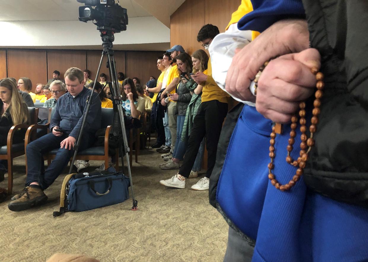 A volunteer for Catholic Worker, which is related to the organization that runs Motels4Now, prays a rosary Feb. 14, 2023, at the St. Joseph County Council meeting in South Bend where people wore yellow to support the program's funding.