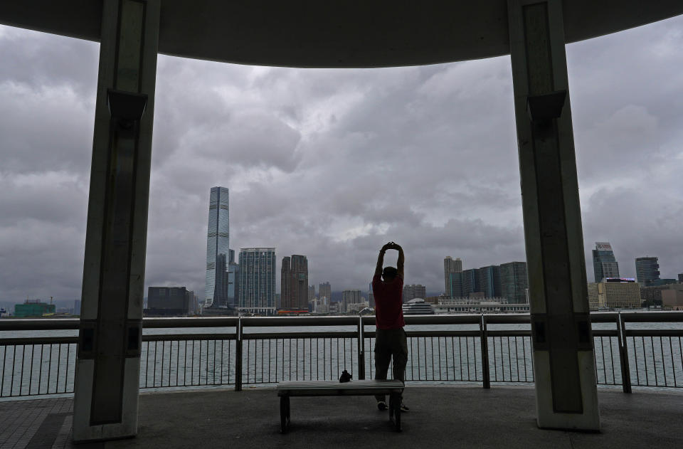 A man raises his arms as he exercises at the waterfront of Victoria Harbour in Hong Kong Wednesday, Aug. 19, 2020. Typhoon Higos weakened to strong topical storm after making landfall in Zhuhai city on Wednesday morning on China's southern coast. (AP Photo/Vincent Yu)