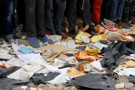 People stand near papers at the site of a collapsed school classroom, in Nairobi