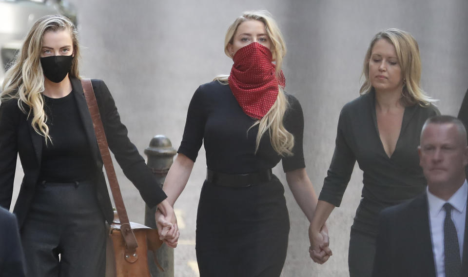 Actress Amber Heard, center, arrives at the High Court in London, Tuesday, July 7, 2020. Johnny Depp has a starring role in a real-life courtroom drama in London, where he is suing a tabloid newspaper for libel over an article that branded him a "wife beater." On Tuesday, a judge at the High Court is due to begin hearing Depp's claim against The Sun's publisher, News Group Newspapers, and its executive editor, Dan Wootton, over the 2018 story alleging he was violent and abusive to then-wife Amber Heard. Depp strongly denies the claim. (AP Photo/Alastair Grant)