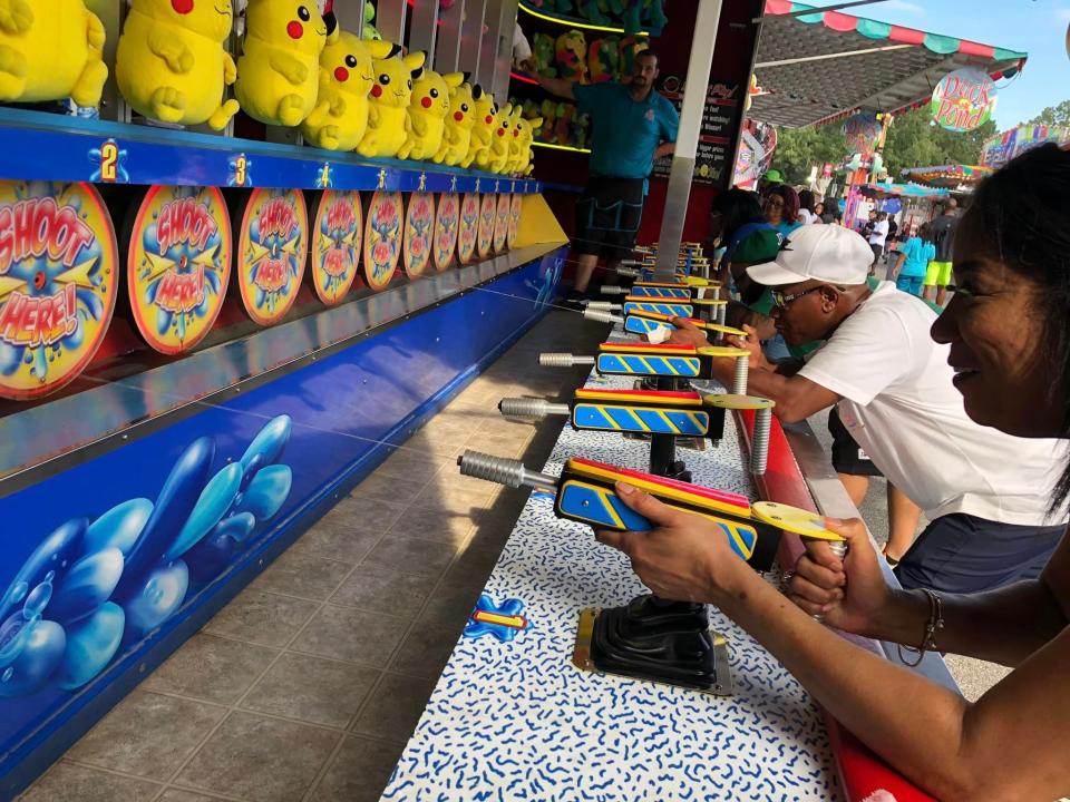 From left to right, Andre Washington and Mystery Briscoe of Petersburg play a squirt gun game at the 2022 Chesterfield County Fair in Chesterfield, Va.