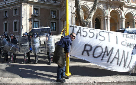 A taxi driver stands next a banner reading " Roman taxi drivers" during a rally in Rome, Italy, February 21, 2017. REUTERS/Alessandro Bianchi