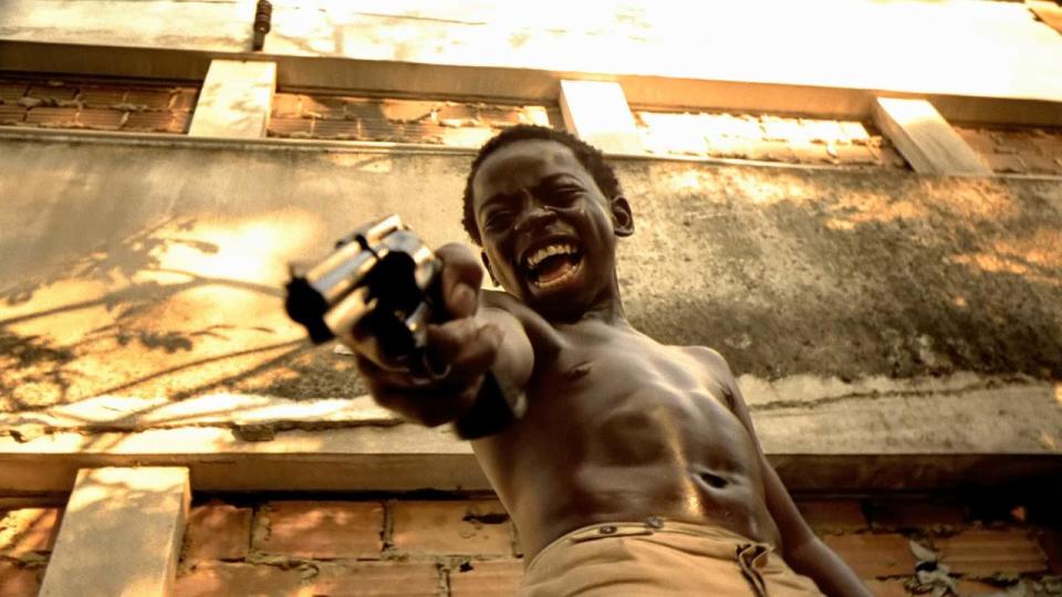 <p> Set in Rio de Janeiro between the 1960’s and 1980’s, City of God follows the life of Rocket (Alejandre Rodrigues), a boy living in the titular favela (low-income Brazilian housing project) who navigates a world ruled by drug wars, the film jumping back and forth between points in his life and the lives of people around him. His older brother, Goose (Renato de Souza), along with Goose's friends Shaggy (Jonathan Haagensen) and Clipper (Jefechander Suplino), run a gang known as the Tender Trio, committing petty crimes and distributing the wealth to the favela's inhabitants. A young kid named Li'l Dice (Douglas Silva) convinces the trio to hold up a hotel and, unsatisfied by the lack of bloodshed, takes it upon himself to gleefully murder everyone inside. The trio disbands, Li'l Dice renames himself Li'l Zé (played as an adult by Leandro Firmina de Hora), and using a gang of children known as "The Runts" eliminates all of the competition save for one dealer named Carrot (Matheus Nachtergaele). Li'l Zé, drunk with power, attacks a peaceful man named Knockout Ned (Seu Jorge) and murders several members of his family; Ned partners with Carrot, and the two sides are enveloped in all-out war. Ned is killed by a boy seeking vengeance, and the police capture Carrot and Zé, keeping Carrot for failing to pay off the police and letting Zé go, who is subsequently killed by Runts looking to take over the business for themselves. Rocket photographs the scene, and has a choice: expose the police's corruption, or use the photo of Zé's body to get an internship with the paper. He chooses the latter. </p> <p> <strong>Key things to mention: </strong>One of the reasons City of God is so powerful is that, other than the actor who plays Carrot, no-one in the film has any professional acting experience. Many of the actors were from favelas in Brazil, several of them from the actual city portrayed in the film. Also, Li'l Zé is <em>horrid</em>; one scene shows him harassing a bunch of Runts, asking them whether they want him to shoot their hands or feet. They hold their hands out, and he shoots their toes, then calls a young boy over named Steak-and-Fries and asks him to kill one of them to see if he has the guts. </p> <p> <strong>Memorable quote: </strong>"Where do you want to take the shot? In the hand or in the foot?"<br> <strong>David Roberts</strong> </p>