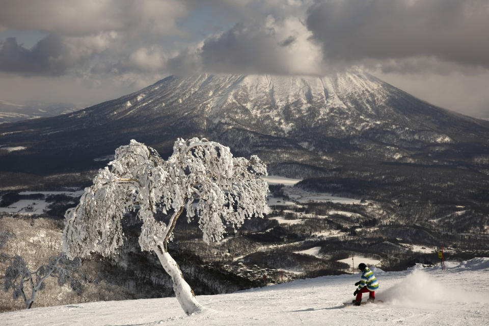 A man snowboards down a slope overlooking Mount Yotei at a ski resort Feb. 5, 2020, in Niseko, Hokkaido, Japan. “There’s a lot less snow,” said Nguyen Nguyen, a skier visiting from Hong Kong. “This is definitely the worst I’ve ever seen it.” (AP Photo/Jae C. Hong)