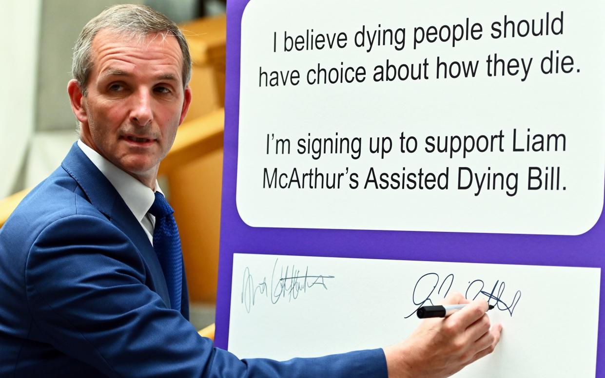 Liam McArthur, the Lib Dem MSP for Orkney, signs a board at the Scottish Parliament during a previous attempt to pass assisted dying legislation in 2022