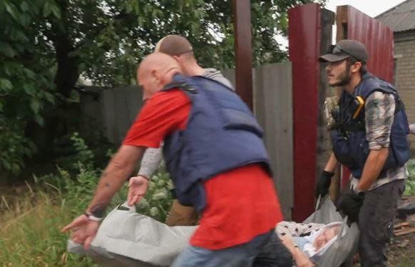 Tony Demczar, 22, from Albany, New York (at right), helps other members of a rescue team move an elderly woman into a van to be evacuated from the town of Chasiv Yar, Ukraine, as Russia's invading forces draw closer, July 2022. / Credit: CBS News