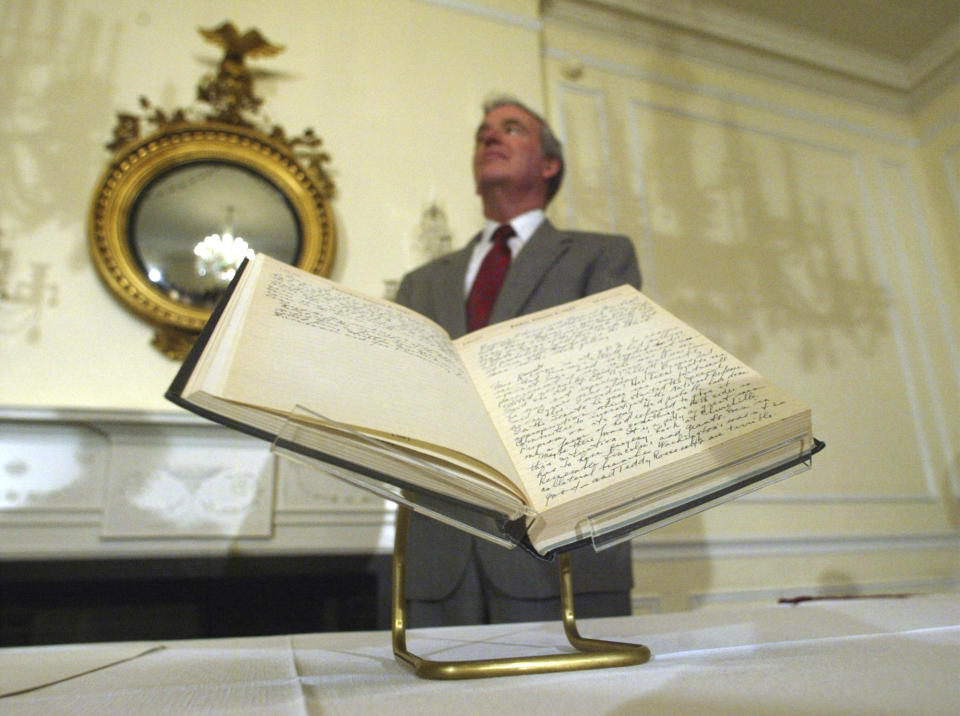 FILE - Archivist of the U.S John Carlin stands behind a 1947 Harry Truman presidential diary, July 10, 2003, at the National Archives in Washington. Presidents from George Washington to Joe Biden have kept presidential diaries. In them, they confide in themselves, express raw opinions, trace even the humdrum habits of their day and offer insight-on-the-fly on monumental decisions of their time. It's where they may also spill secrets they shouldn't. (AP Photo/Rick Bowmer, File)