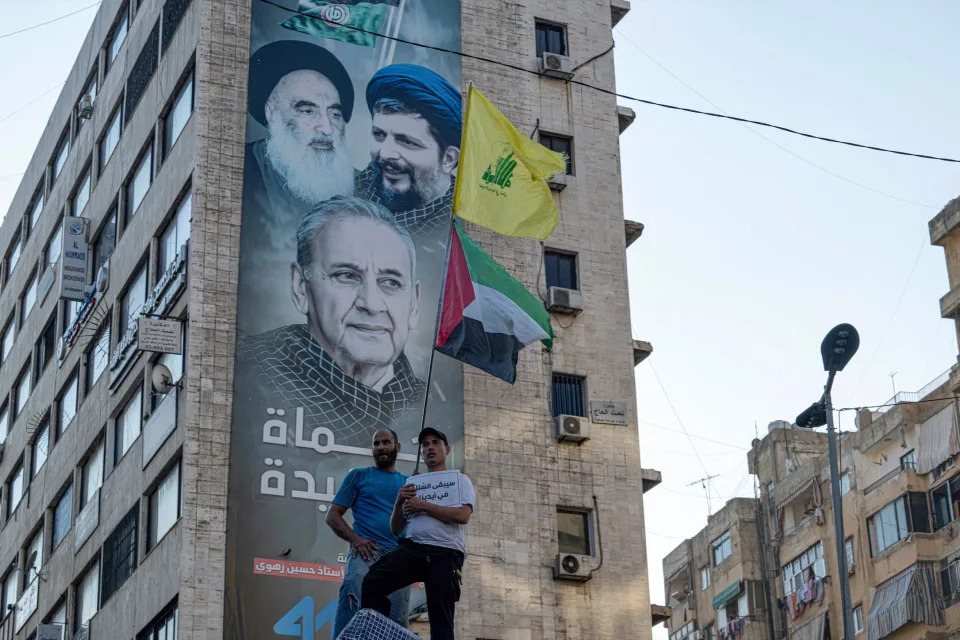 A man waves a Hezbollah and a Palestinian flag during the funeral procession of top Hezbollah commander Fuad Shukr in Beirut's southern suburbs on August 1.