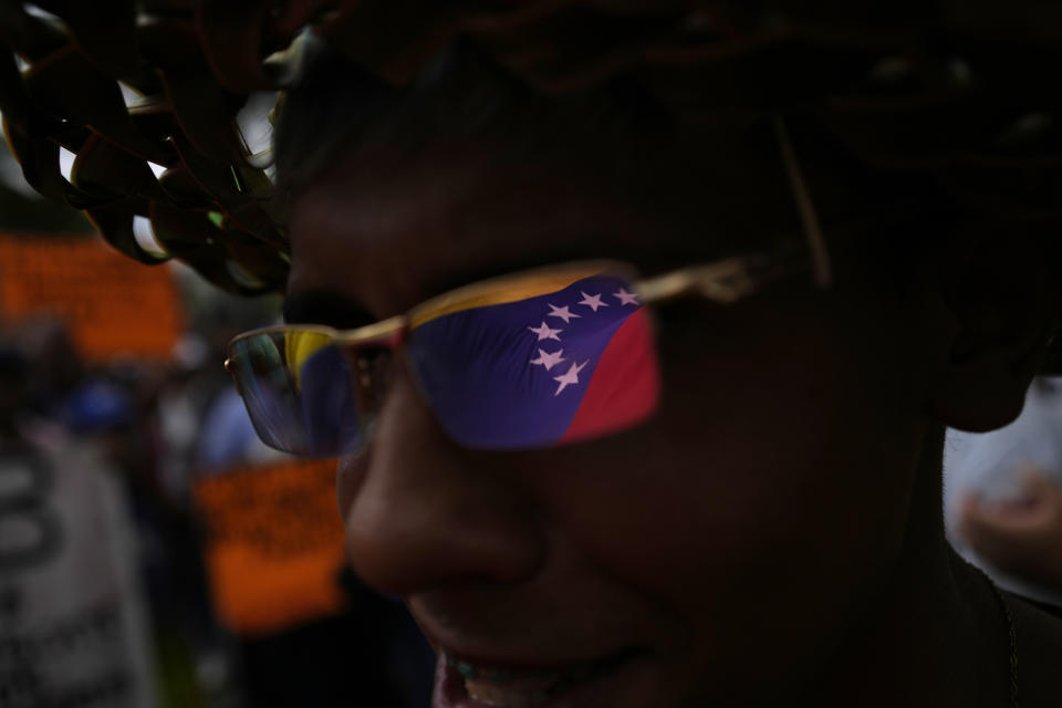 FILE - A Venezuelan flag is reflected in the sunglasses of a student federation member during a protest by public workers demanding the government pay their full benefits and respect collective bargaining agreements in Caracas, Venezuela, Thursday, Aug. 11, 2022. (AP Photo/Matias Delacroix, File)