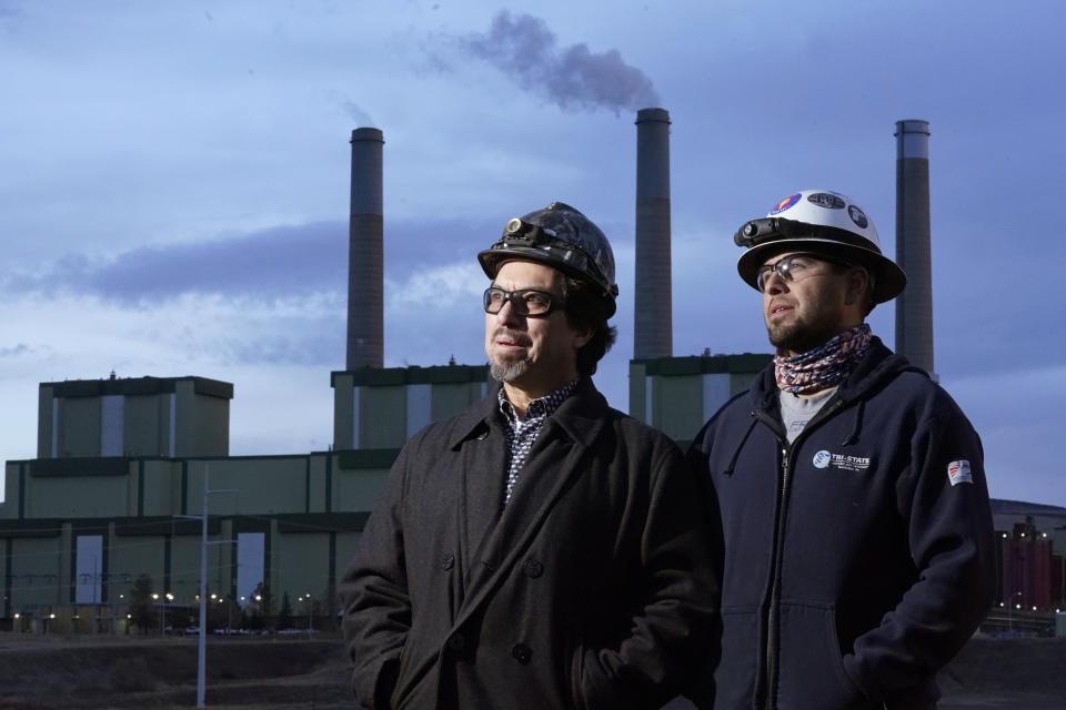 Trinidad Loya, left, stands next to his son Trini Loya lll, as they pose for a photo near the Craig Station on Thursday, Nov. 18, 2021, in Craig, Colo. The coal plant in Craig is closing, along with the mine that feeds it and all the workers will lose their jobs over the next decade. For the Loyas, as for other coal families, the power plant afforded them a lifestyle they wouldn't have had otherwise. (AP Photo/Rick Bowmer)