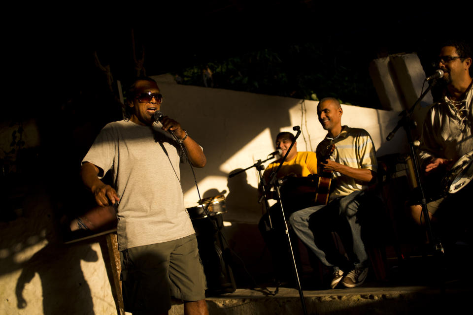 In this Sept. 15, 2012 photo, Luiz Pinto, left, sings samba in the Quilombo Sacopa in Rio de Janeiro, Brazil. To Pinto and his family, this was much more than a party. They were trying to save the grouping of brick houses and shacks nestled in the lush foilage of Brazil’s coastal rainforest where Pinto’s ancestors have made their home for more than century but never legally owned. They first arrived more than a century ago as escaped slaves hiding out in a nearby cave. (AP Photo/Victor R. Caivano)