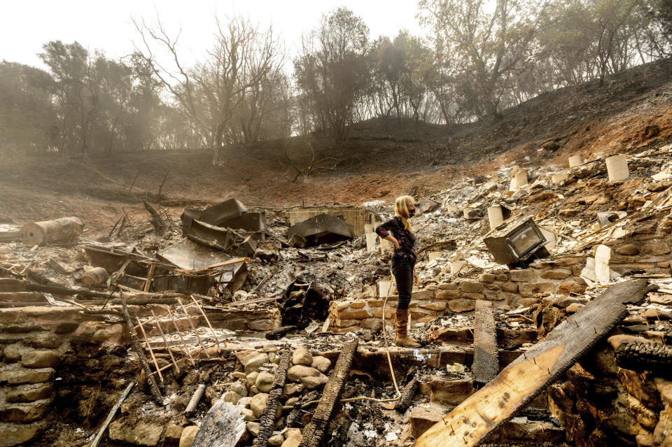 Pam, who declined to give a last name, examines the remains of her partner's Vacaville, Calif., home on Friday, Aug. 21, 2020. The residence burned as the LNU Lightning Complex fires ripped through the area Tuesday night. (AP Photo/Noah Berger)