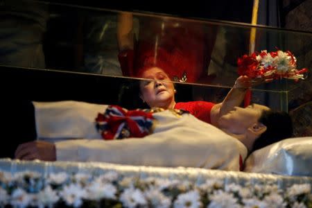 FILE PHOTO - Former first lady Imelda Marcos offers flowers on the glass coffin of her husband, late president Ferdinand Marcos, who remains unburied since his death in 1989, during her 85th birthday celebration in Ferdinand Marcos' hometown of Batac, Ilocos Norte province, in northern Philippines July 2, 2014. REUTERS/Erik De Castro/File Photo