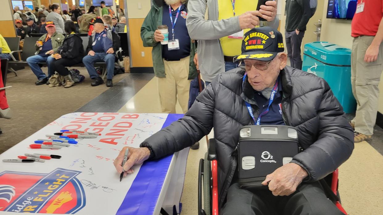 The lone World War II veteran on the Blue Ridge Honor Flight on Oct. 1 signs a banner at the Asheville Regional Airport prior to departure.