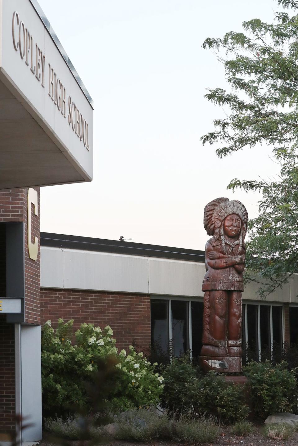 A wooden carved statue stands near the entrance of Copley High School.