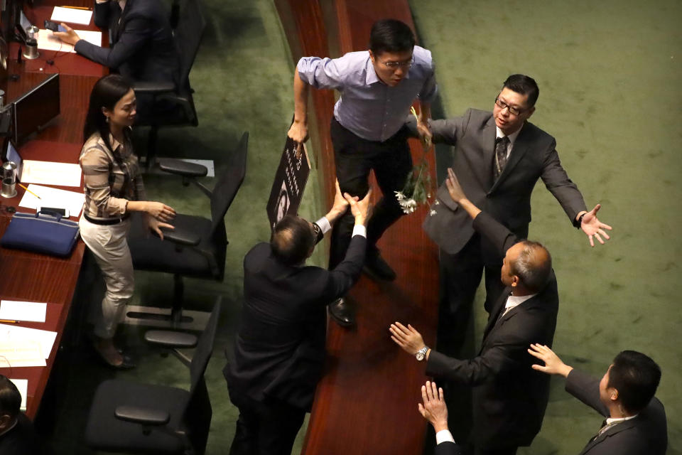 Security officers pursue pro-democracy lawmaker Au Nok-hin, center, as he runs across desks to chase Hong Kong Chief Executive Carrie Lam leaving a question and answer session with lawmakers at the Legislative Council in Hong Kong, Thursday, Oct. 17, 2019. (AP Photo/Mark Schiefelbein)