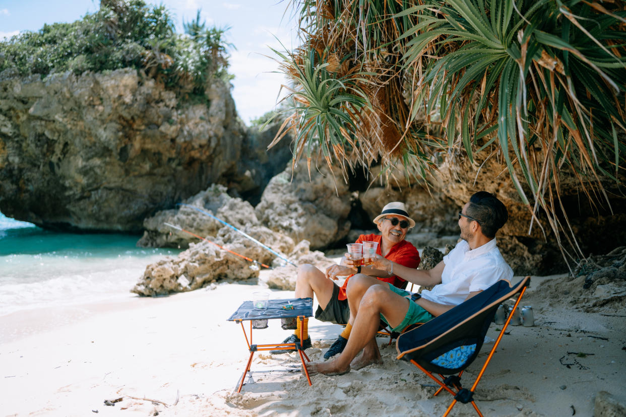 Father and son having a toast at beach campsite in Okinawa, Japan, a senior-friendly travel destination. (Photo: Gettyimages)