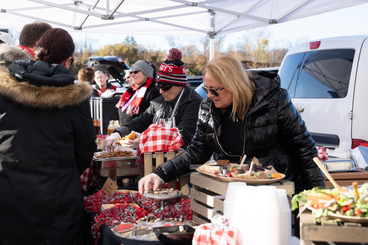 Kelly Pleimann, catering manager of Hoggy’s Catering, hands out food at one of four tailgates on Saturday, Nov. 18, 2023 at Ohio Stadium.