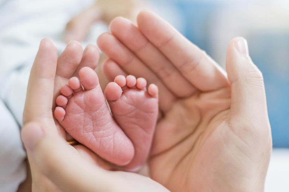 A parent holds the feet of their newborn baby