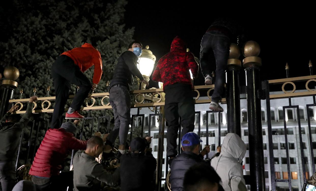 Opposition protesters storm the gates of the parliamentary building, known as the 'White House', in Bishkek (EPA)