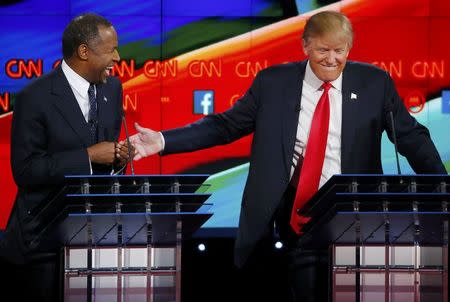 Republican U.S. presidential candidate businessman Donald Trump (R) reacts to a comment from Dr. Ben Carson (L) and reaches over to him in the midst of the Republican presidential debate in Las Vegas, Nevada December 15, 2015. REUTERS/Mike Blake