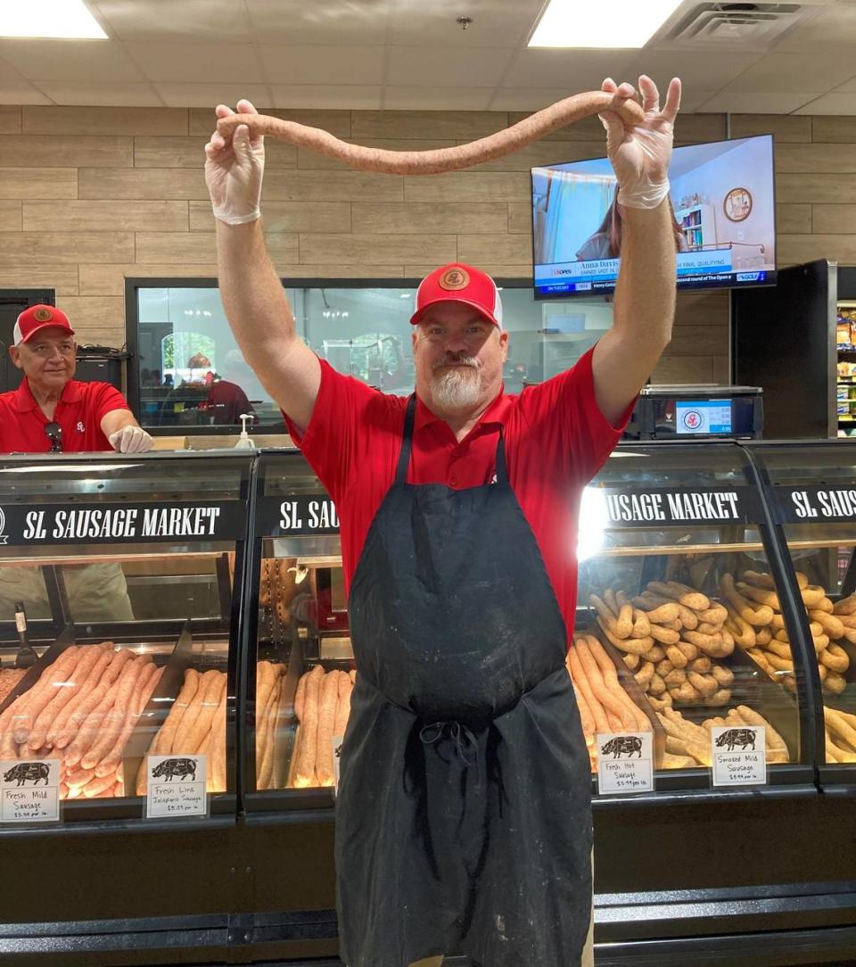Matt Womack holds up a link of sausage at the newly-opened SL Sausage Company in Macon while co-worker Buddy Roper looks on. Becky Purser /The Telegraph