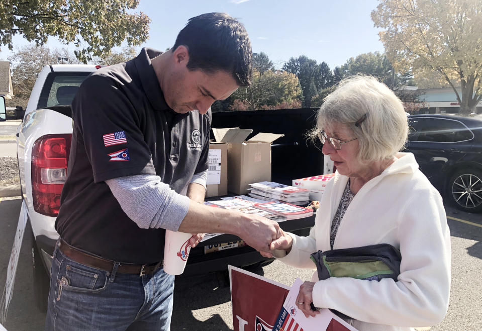 Ruth Boone offers a prayer for Ohio’s Republican Secretary of State, Frank LaRose, after picking up a LaRose lawn sign from canvassers at a Kroger’s parking lot, Sunday, Oct. 23, 2022, in Groveport, Ohio. (AP Photo/Jill Colvin)