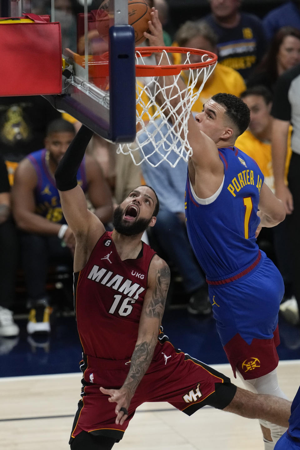 Denver Nuggets forward Michael Porter Jr., right, blocks a shot by Miami Heat forward Caleb Martin during the first half of Game 1 of basketball's NBA Finals, Thursday, June 1, 2023, in Denver. (AP Photo/David Zalubowski)