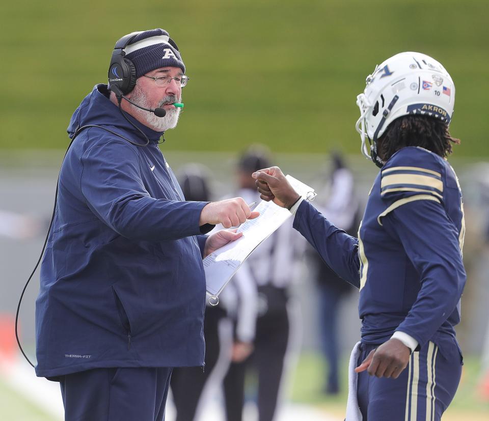 University of Akron head coach Joe Moorhead gives a fist bump to quarterback Tahj Bullock after a second-quarter touchdown against Ohio on Friday, Nov. 24, 2023.