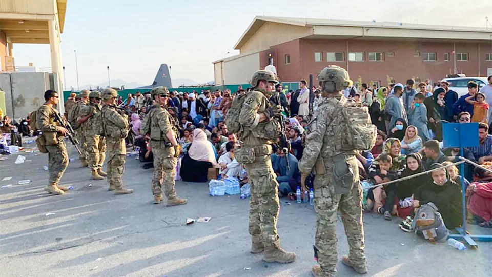 Seen here, US soldiers stand guard as Afghan civilians wait to board a US military aircraft to leave the country in August.