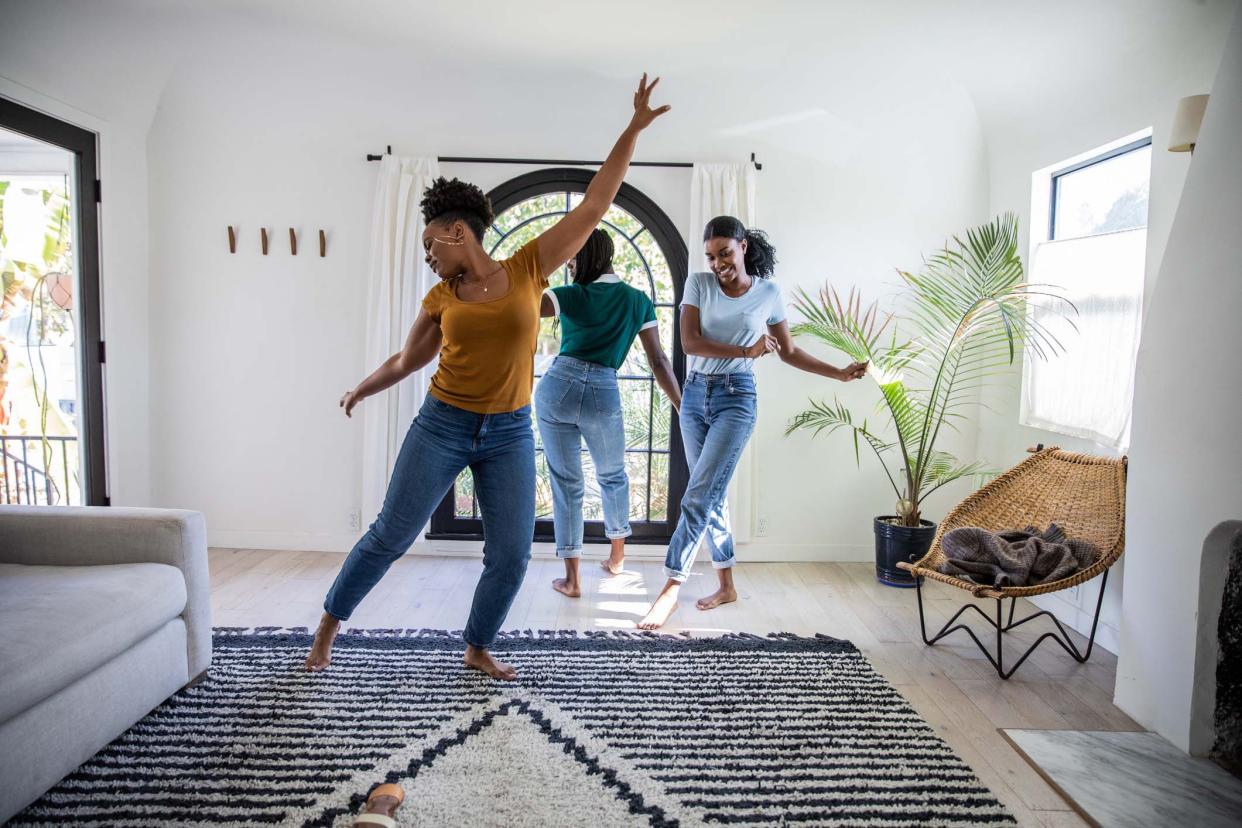 Women friends having fun at home dancing and singing in the living room of their Los Angeles apartment.