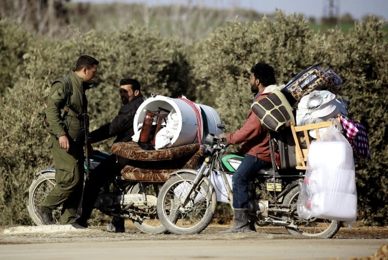 A member of the Syrian Democratic Forces (SDF)(L) checks displaced Syrian men waiting at a checkpoint near a makeshift camp for displaced people near the town of Manbij, northern Syria on March 6, 2017