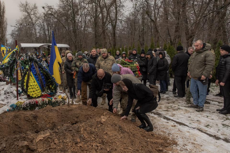 Relatives and friends toss handfuls of soil over the coffin during the funeral service of Ukrainian serviceman Sergiy Pavlichenko, who was killed fighting Russian troops in the Zaporizhzhia region, at a cemetery in Kyiv (AFP via Getty Images)