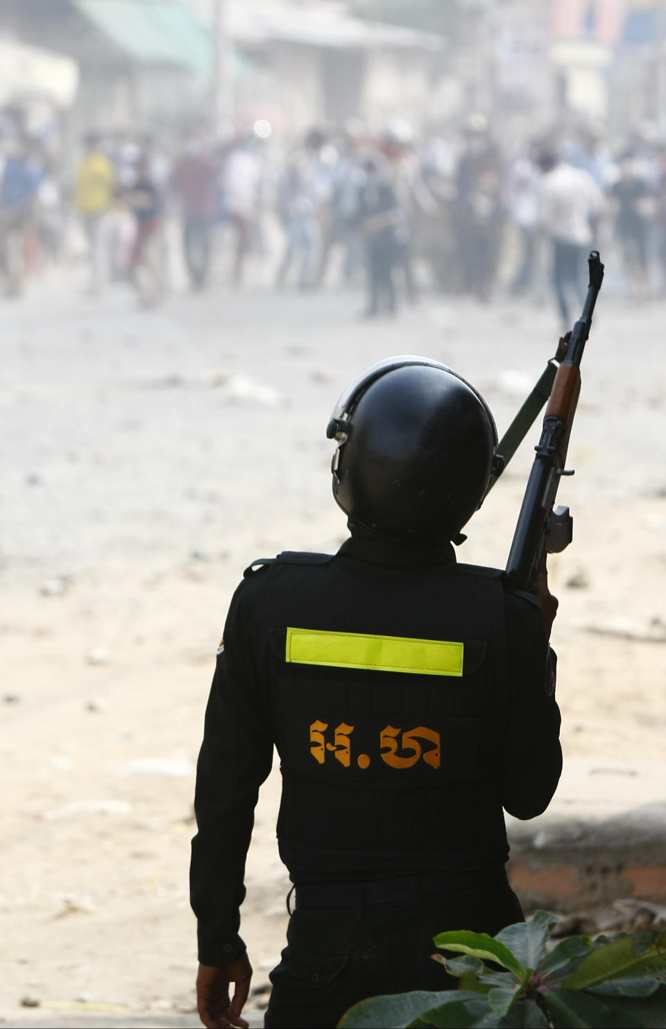 A Cambodia riot police holding a rifle confronts the protesters of garment workers on strike near a factory of Canadia Center, on the Stung Meanchey complex at the outskirt of Phnom Penh, Cambodia, Friday, Jan. 3, 2014. A police official says at least three people are dead and several wounded after police in Cambodia opened fire Friday to break up a labor protest by striking garment workers. (AP Photo/Heng Sinith)