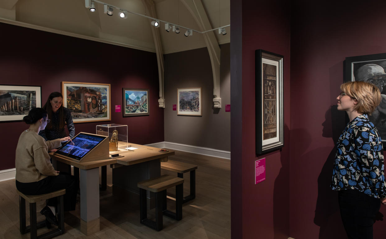 People walk through the Last Cage Down exhibition at the Mining Art Gallery