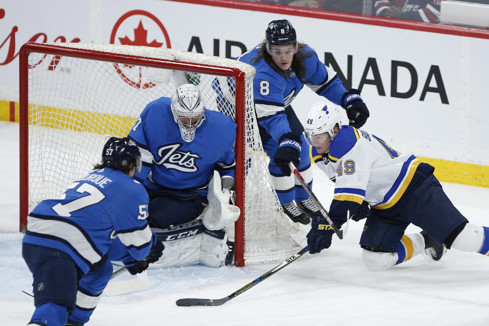 St. Louis Blues' Ivan Barbashev (49) attempts the wraparound on Winnipeg Jets goaltender Connor Hellebuyck (37) as Jets' Gabriel Bourque (57) and Sami Niku (8) defend during the third period of an NHL hockey game Saturday, Feb. 1, 2020, in Winnipeg, Manitoba. (John Woods/The Canadian Press via AP)
