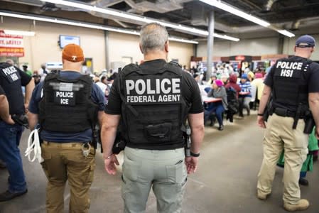 Officers from Immigration and Customs Enforcement (ICE) look on after executing search warrants and making some arrests at an agricultural processing facility in Canton