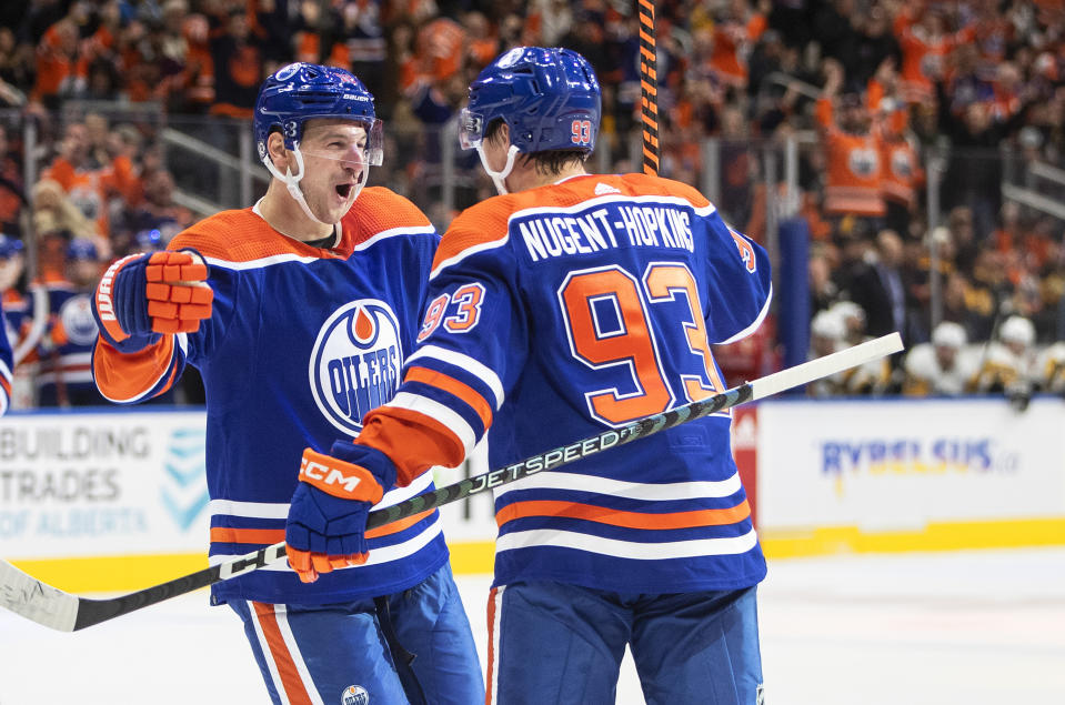 Edmonton Oilers' Zach Hyman (18) and Ryan Nugent-Hopkins (93) celebrate a goal against the Pittsburgh Penguins during second-period NHL hockey game action in Edmonton, Alberta, Monday, Oct. 24, 2022. (Jason Franson/The Canadian Press via AP)