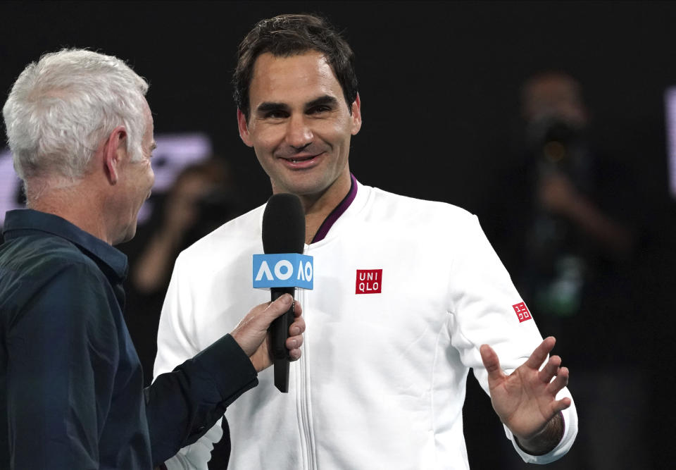 Switzerland's Roger Federer, right, reacts as he is interviewed by John McEnroe after defeating Hungary's Marton Fucsovics in their fourth round singles match at the Australian Open tennis championship in Melbourne, Australia, Sunday, Jan. 26, 2020. (AP Photo/Lee Jin-man)