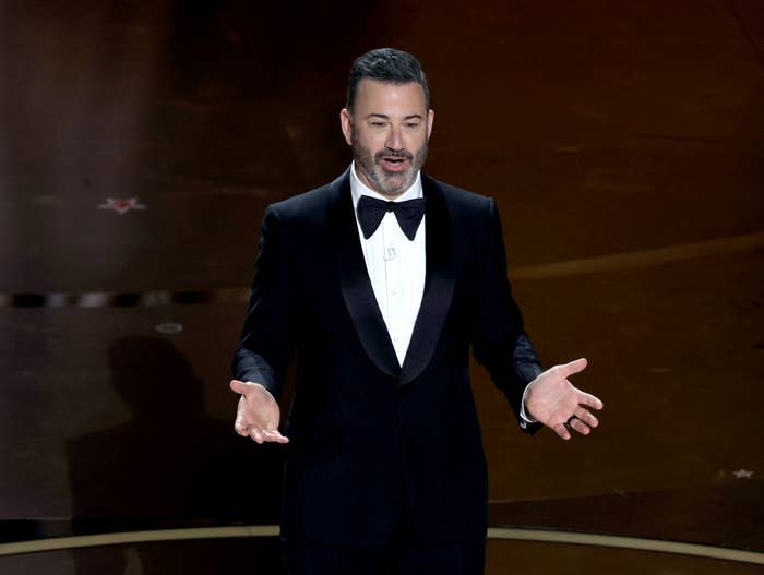 Person in a black tuxedo with bow tie speaking on stage