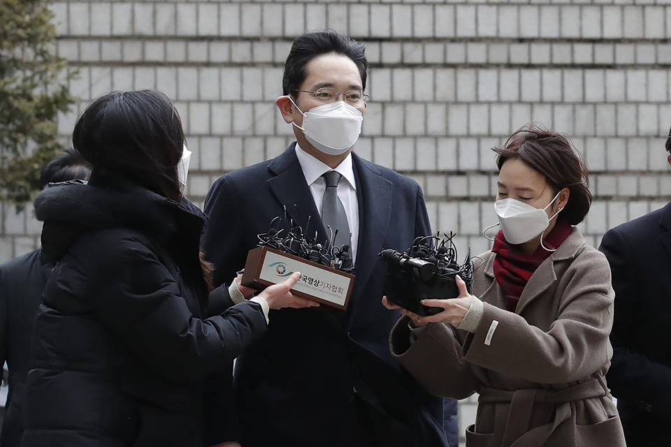 Samsung Electronics Vice Chairman Lee Jae-yong, center, is questioned by reporters upon his arrival at the Seoul High Court in Seoul, South Korea, Monday, Jan. 18, 2021. Lee was sent back to prison on Monday after a South Korean court sentenced him to two and a half years over his involvement in a 2016 corruption scandal that spurred massive street protests and ousted South Korea’s then-president. (AP Photo/Lee Jin-man)