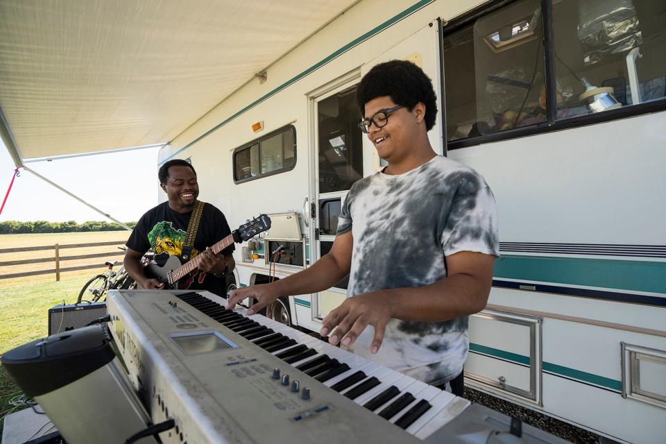 Roland and Clement Kemokai play music outside their RV in Granger. The family, which was nominated by Health Alliance for Austin Musicians, lives in the poorly insulated RV after being hit by apartment rent that doubled.